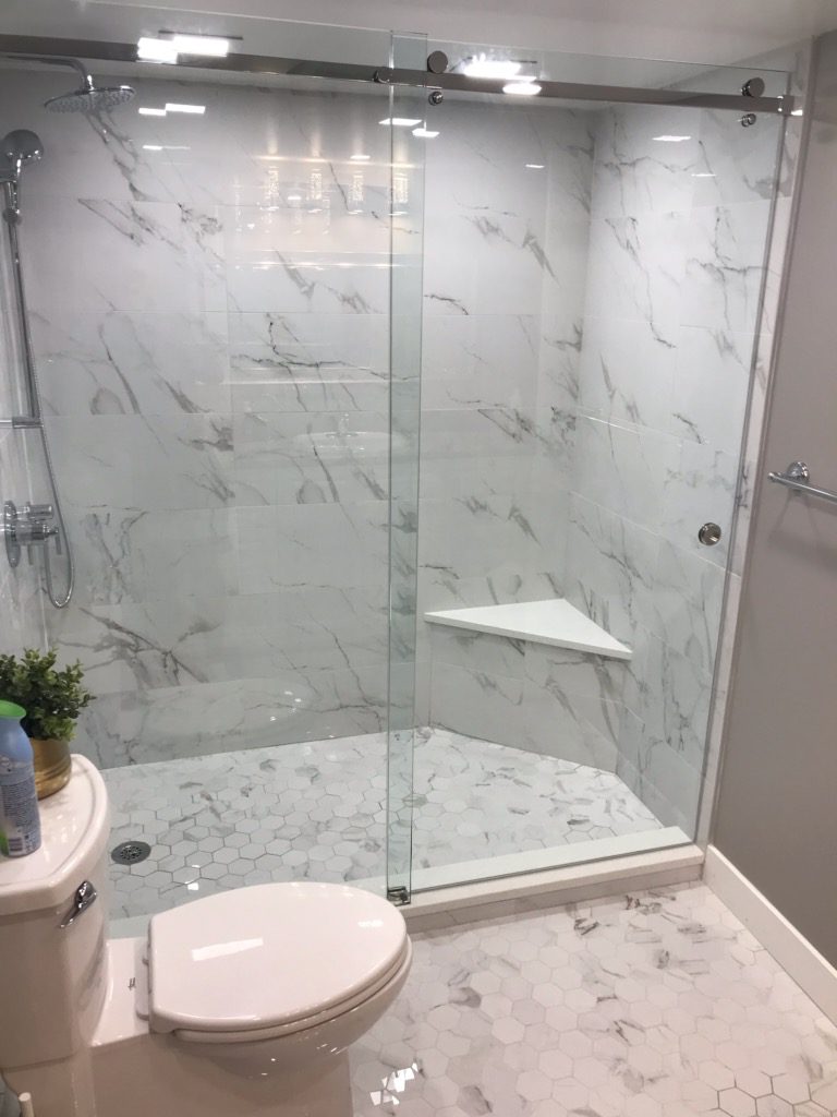 Modern bathroom renovation in Delta BC with heated tile floor, frameless glass shower, and stone vanity by West Coast Home Projects